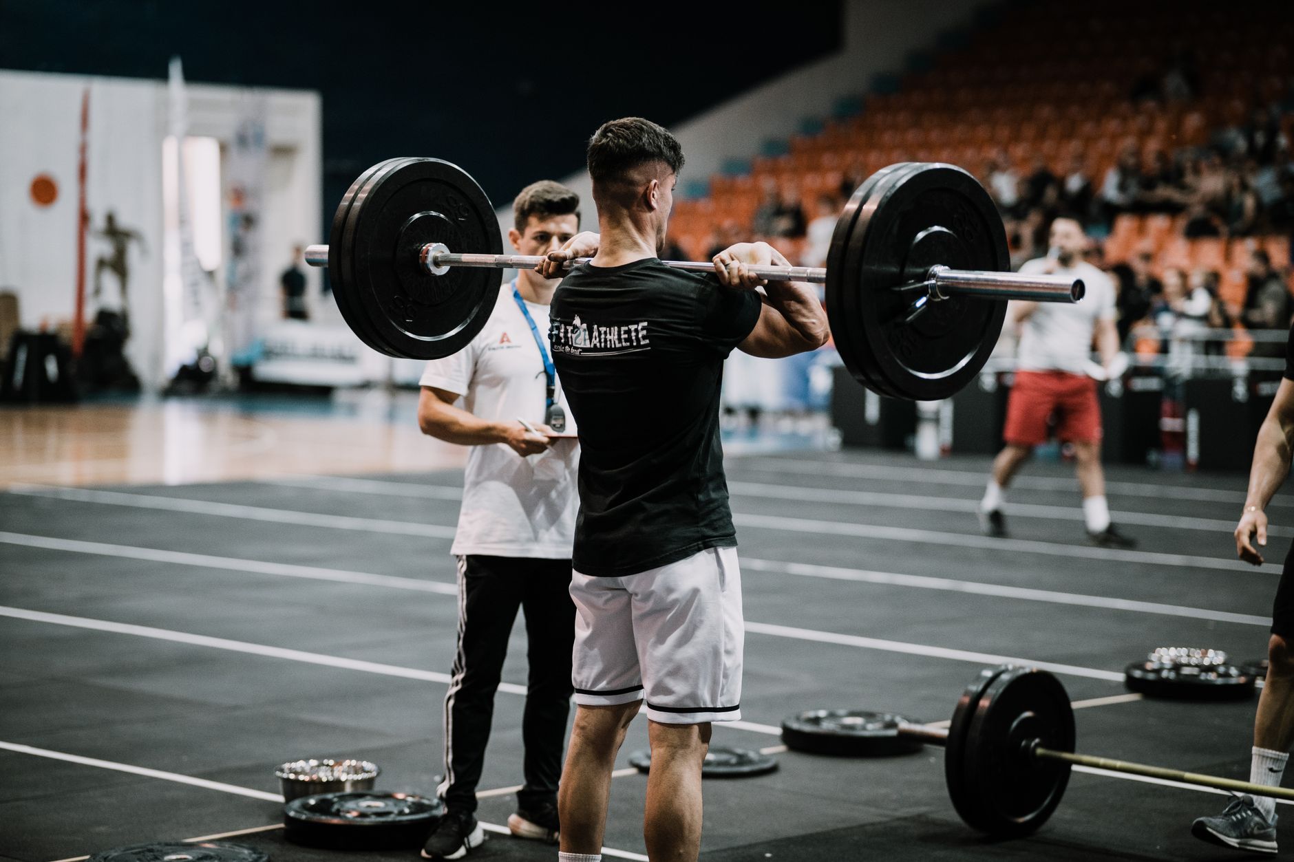 An athlete performs a challenging lift during a weightlifting competition indoors.