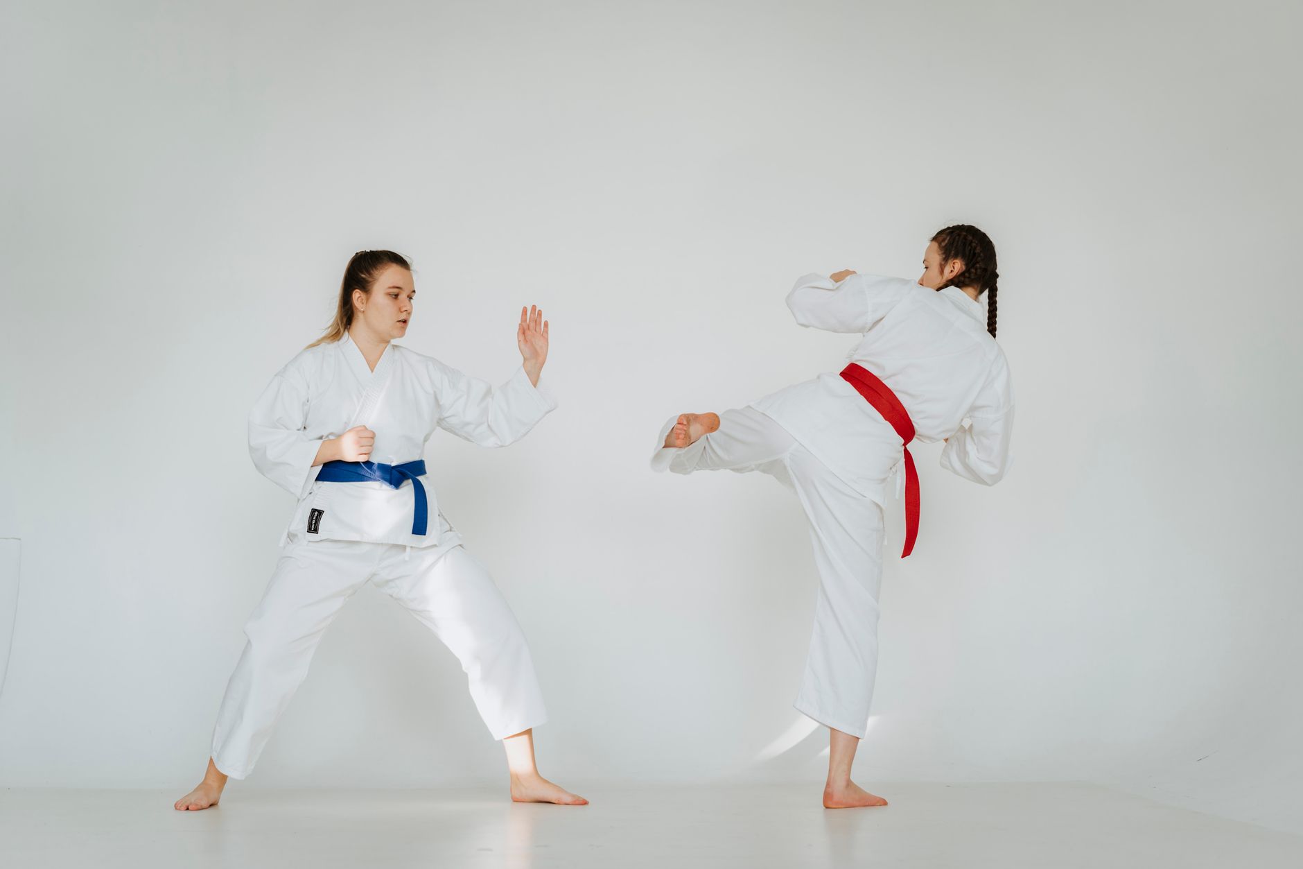 Karate sparring practice with two young women showcasing skill and technique in traditional attire.