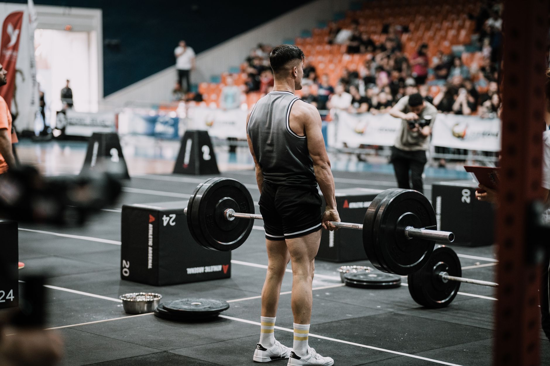 Young male athlete weightlifting at an indoor sports event showcasing strength and endurance.
