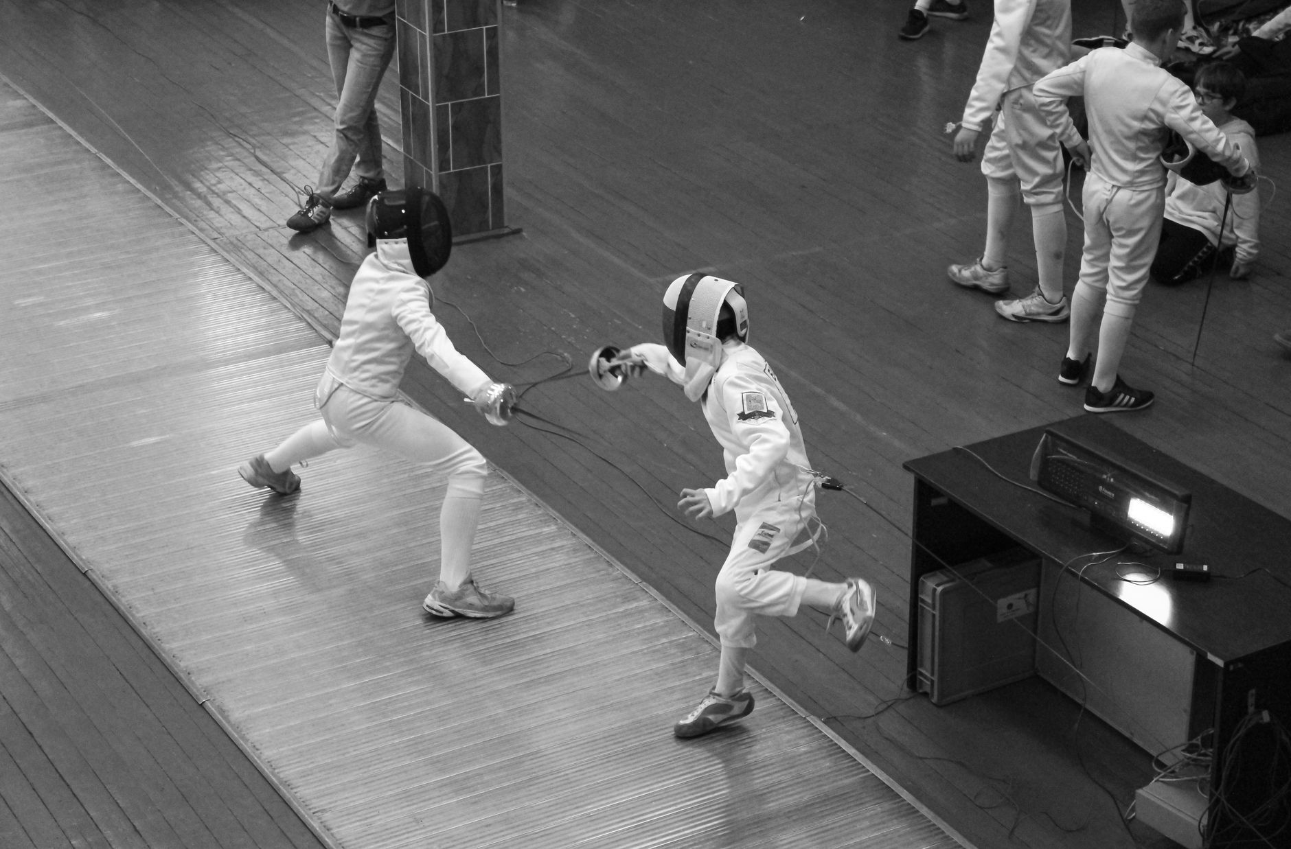 Two fencers in an engaging duel at an indoor competition, showcasing skill and agility.
