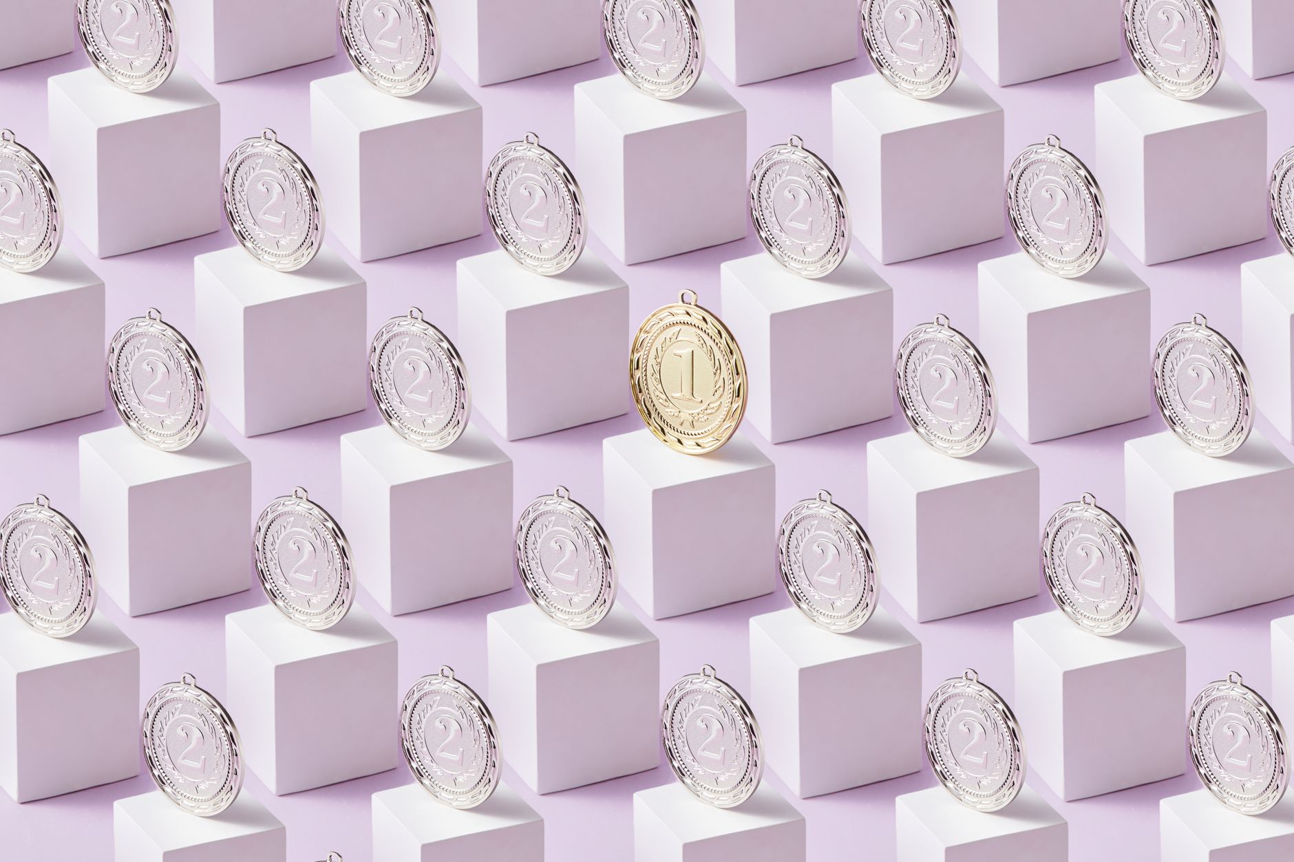 A gold medal stands out among silver medals on white cubes, showcasing uniqueness.