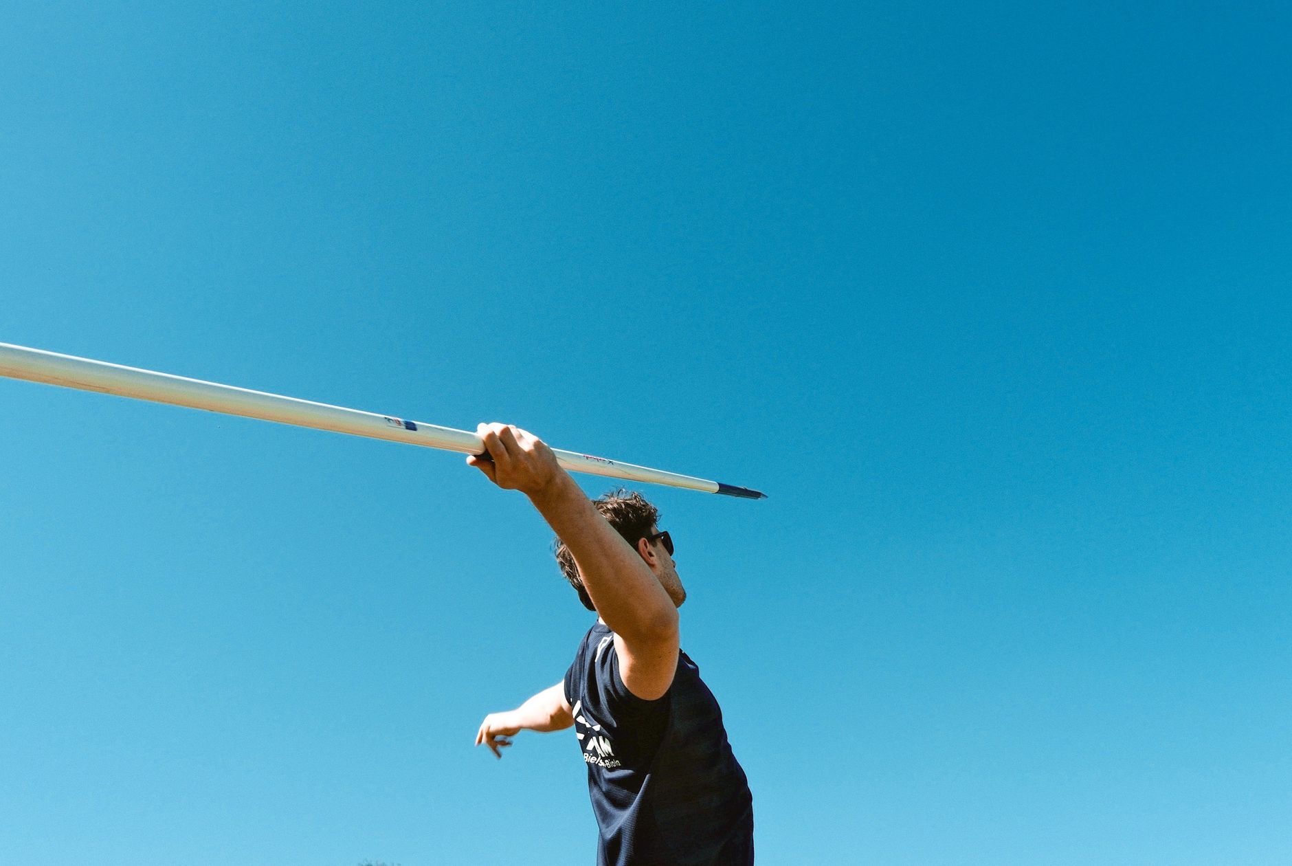 A young athlete prepares to throw a javelin outdoors on a sunny day, capturing the essence of competitive sports.
