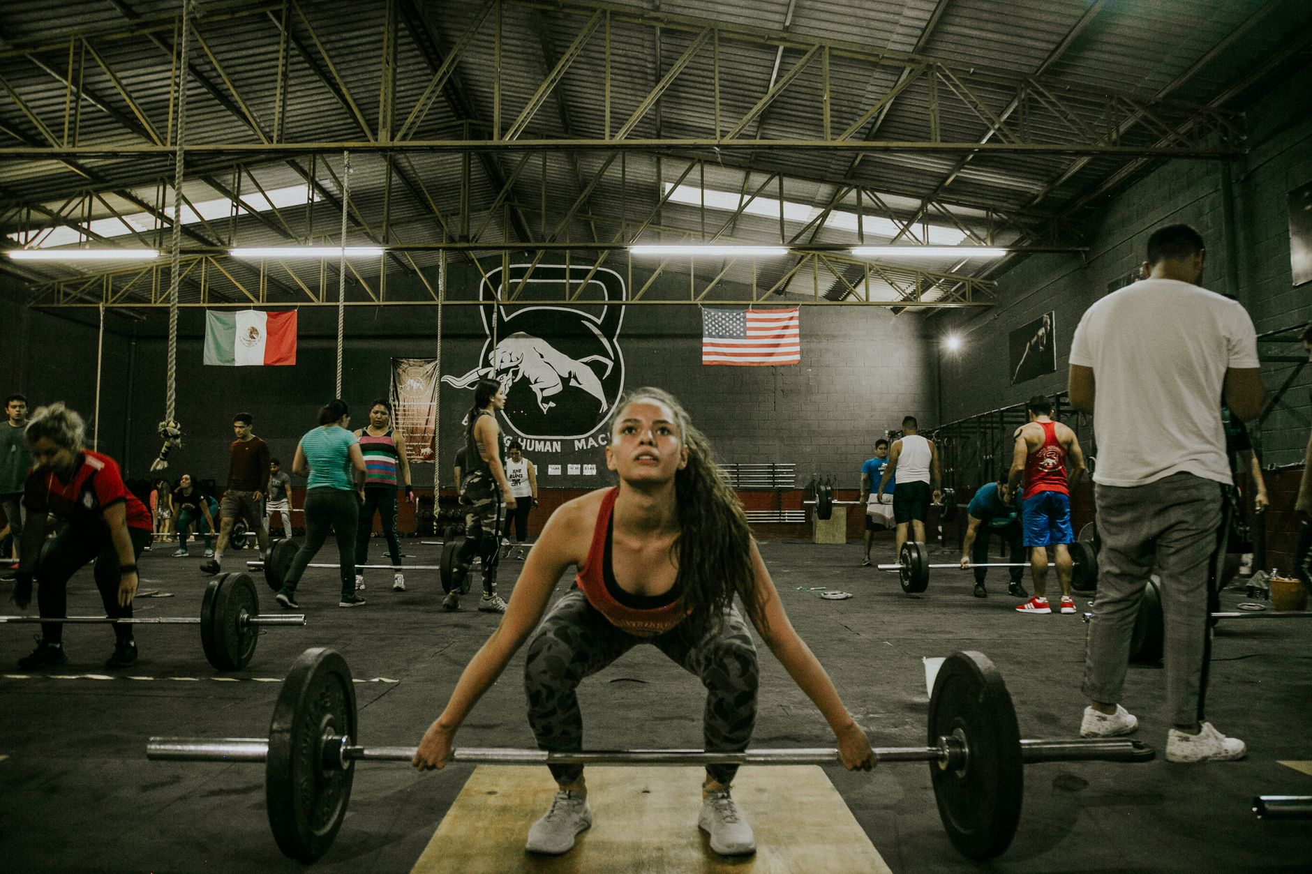 A diverse group of people engage in weightlifting at an indoor gym. Motivated focus.