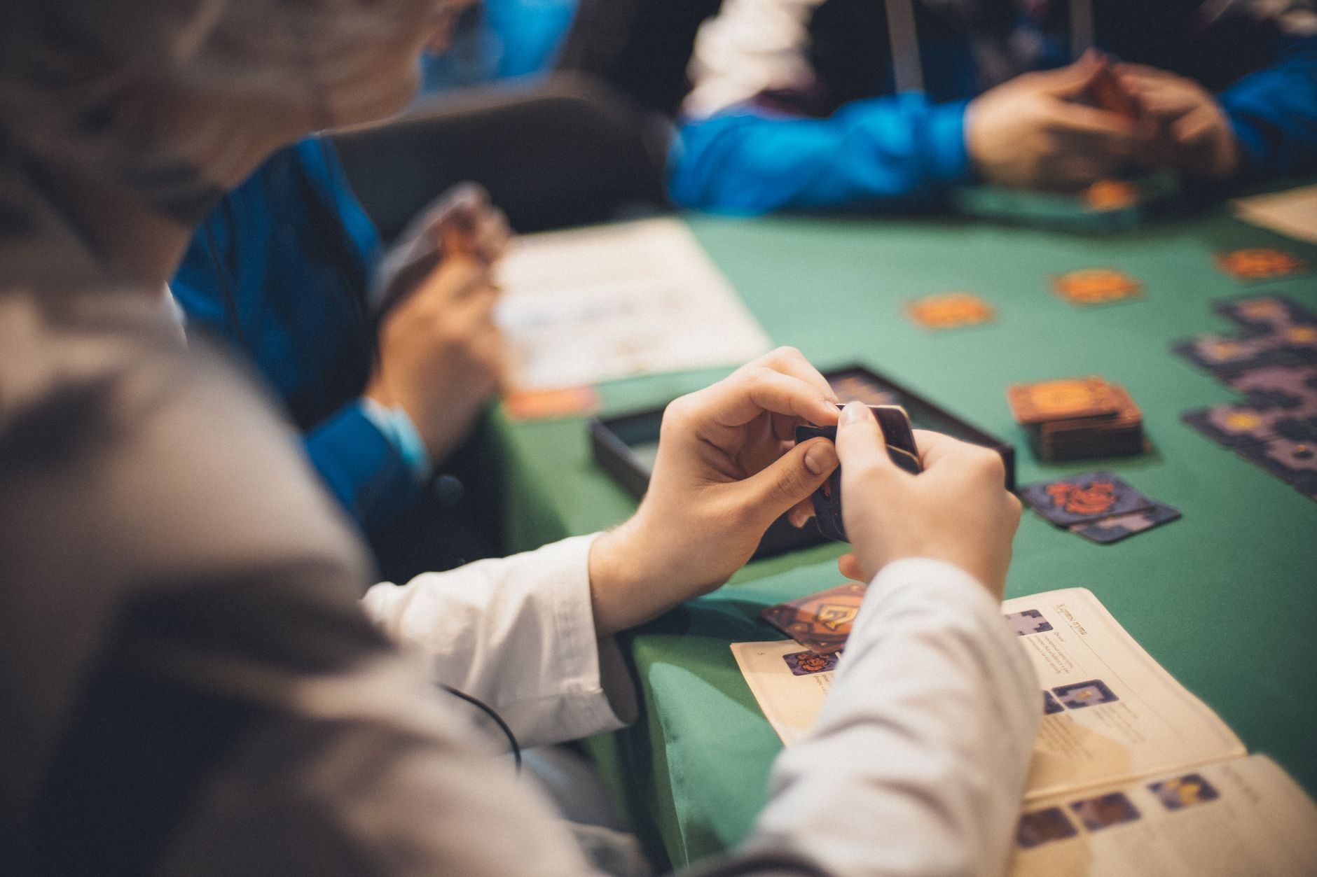 High angle group of crop anonymous people playing card game sitting at table in casino