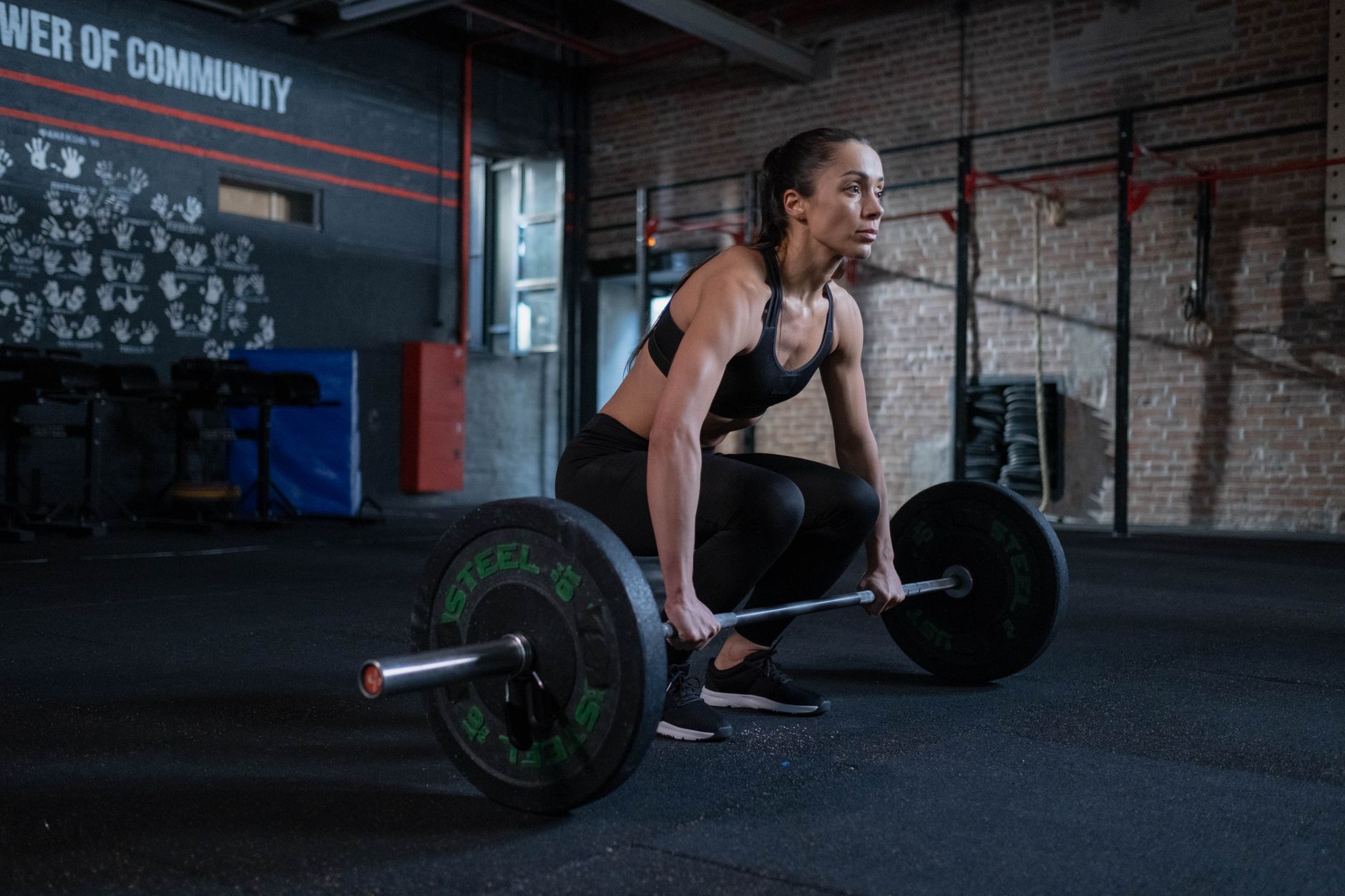 A determined woman prepares to lift barbell in a gym, showcasing strength and focus.