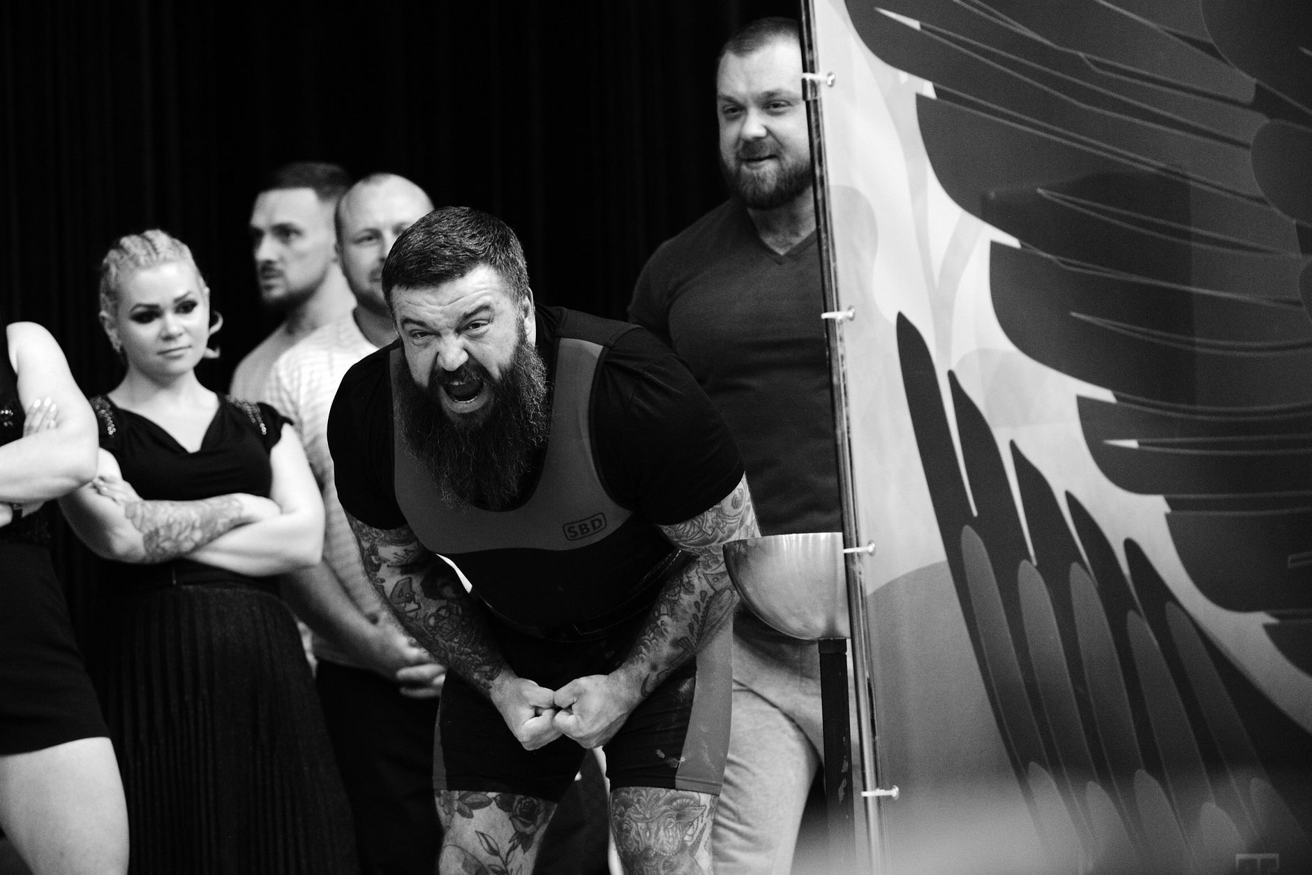 A bearded athlete shows intense emotion during a weightlifting competition.