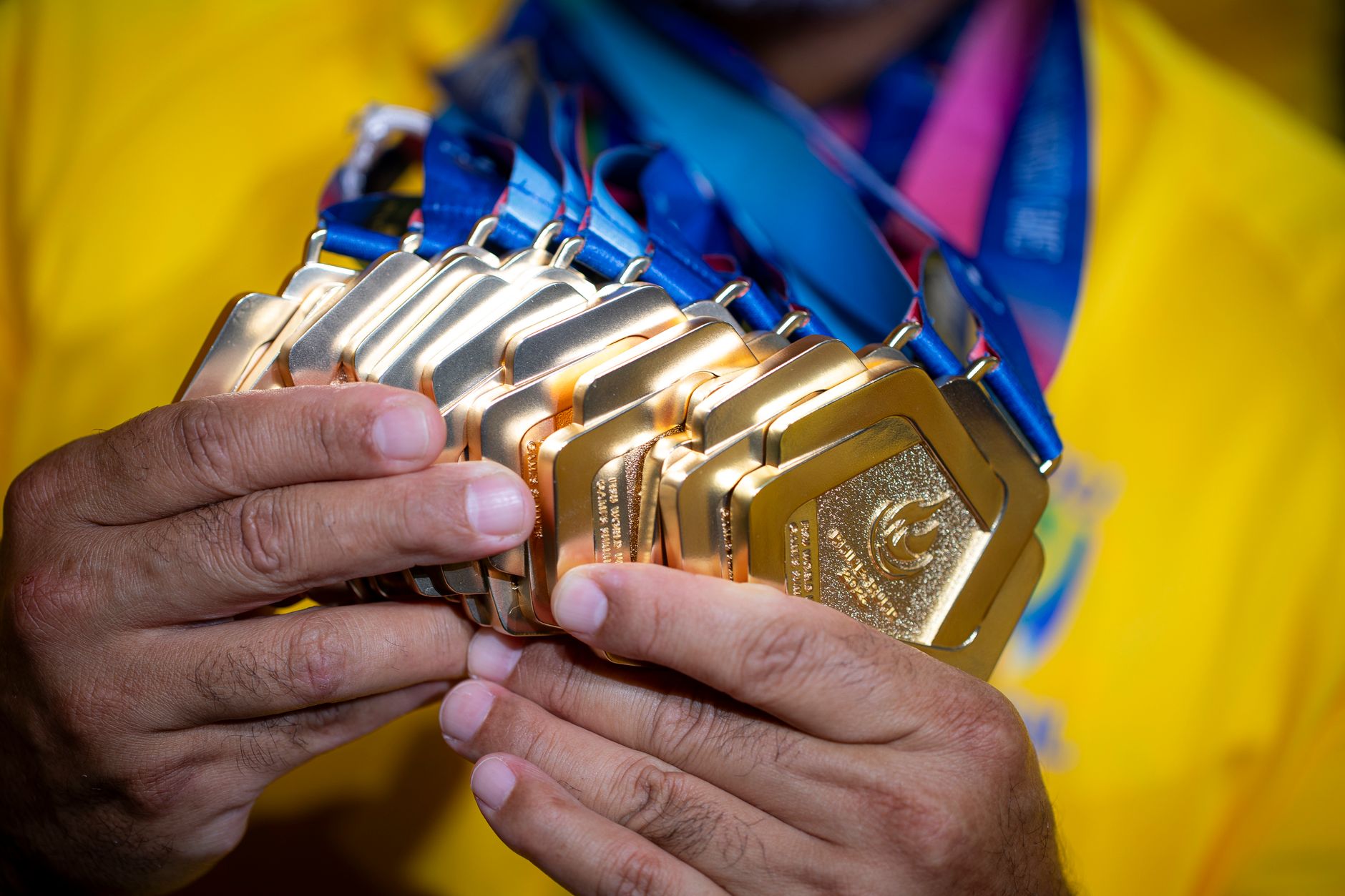 An athlete proudly holds numerous gold medals, showcasing victory and achievement.