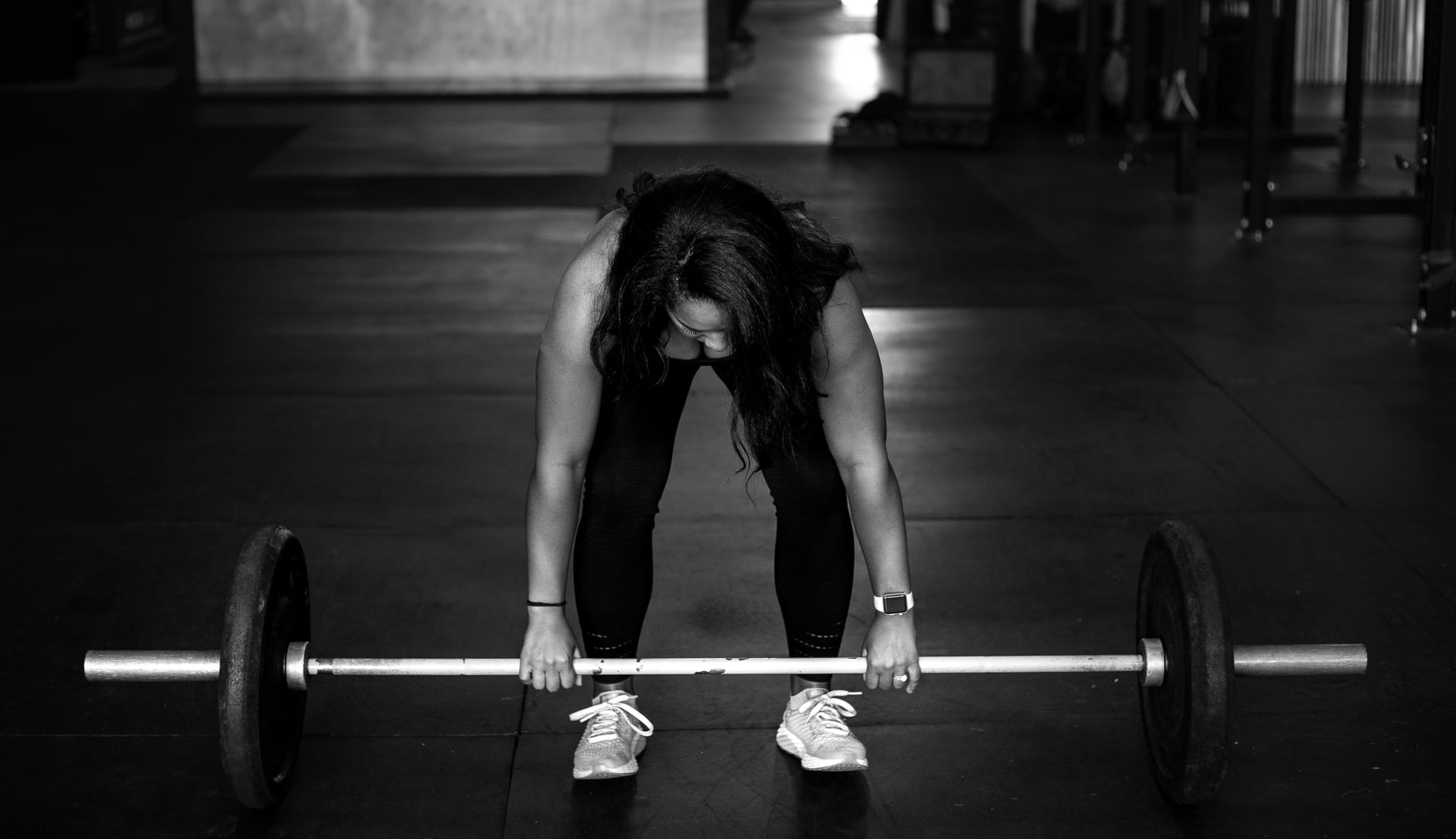 A woman preparing to lift a barbell in a gym, showcasing strength and focus.