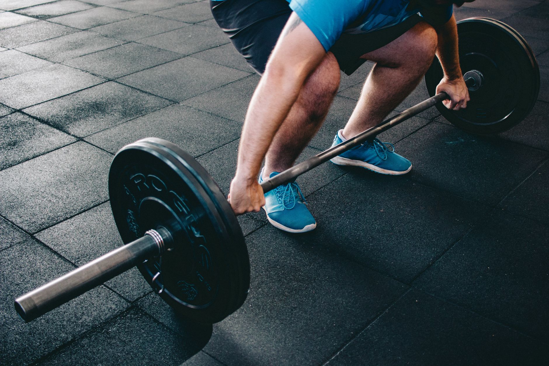 A man deadlifting a barbell indoors showcasing power, fitness, and dedication.